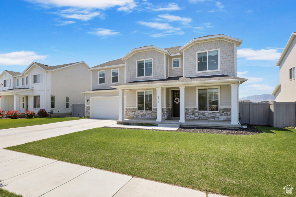 View of front of house featuring a porch, stone siding, concrete driveway, and a garage