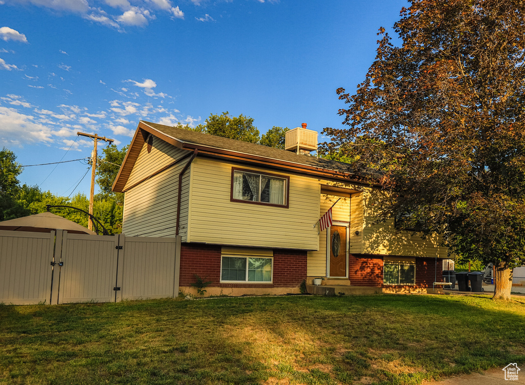 Raised ranch with a gate, a chimney, and brick siding