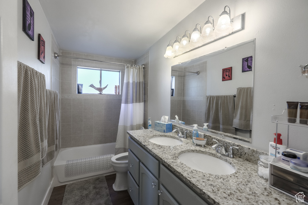 Bathroom with shower / bath combination with curtain, double vanity, and wood finished floors