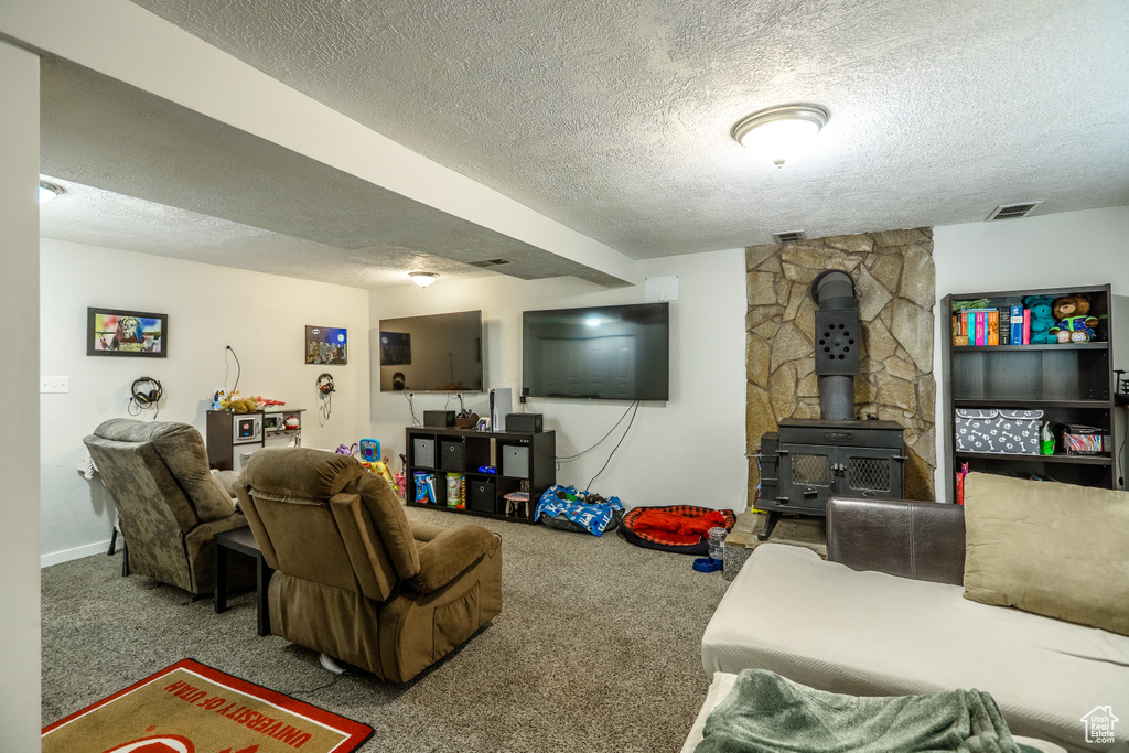 Living room featuring a textured ceiling, carpet flooring, and a wood stove