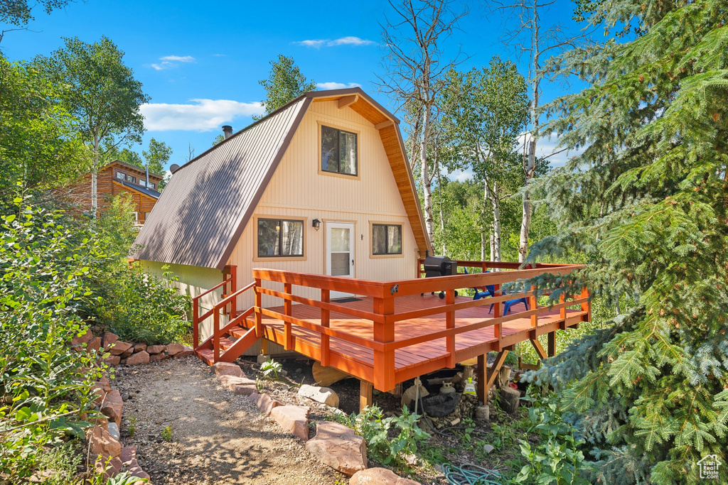 Back of house featuring a metal roof, a gambrel roof, and a deck
