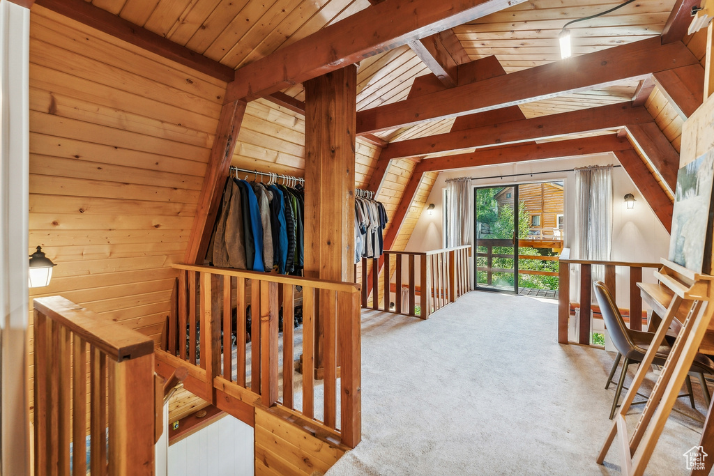 Hall with an upstairs landing, wooden walls, carpet flooring, and wood ceiling