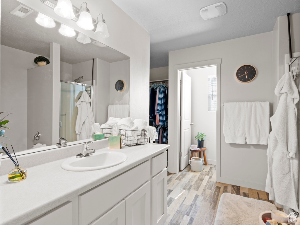 Bathroom with a shower stall, wood finished floors, vanity, and a spacious closet