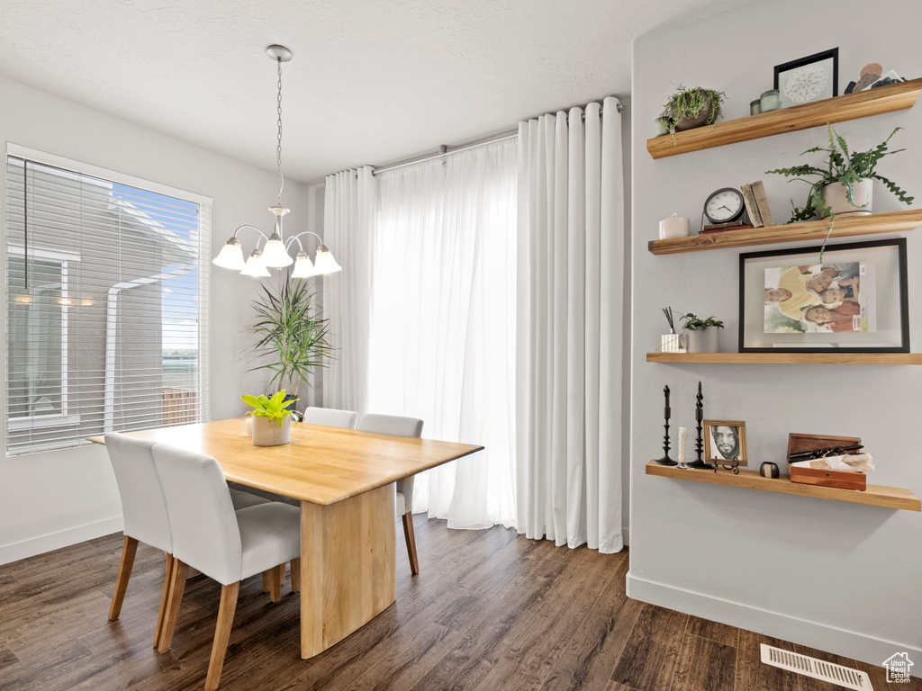 Dining room with a chandelier and dark wood-type flooring
