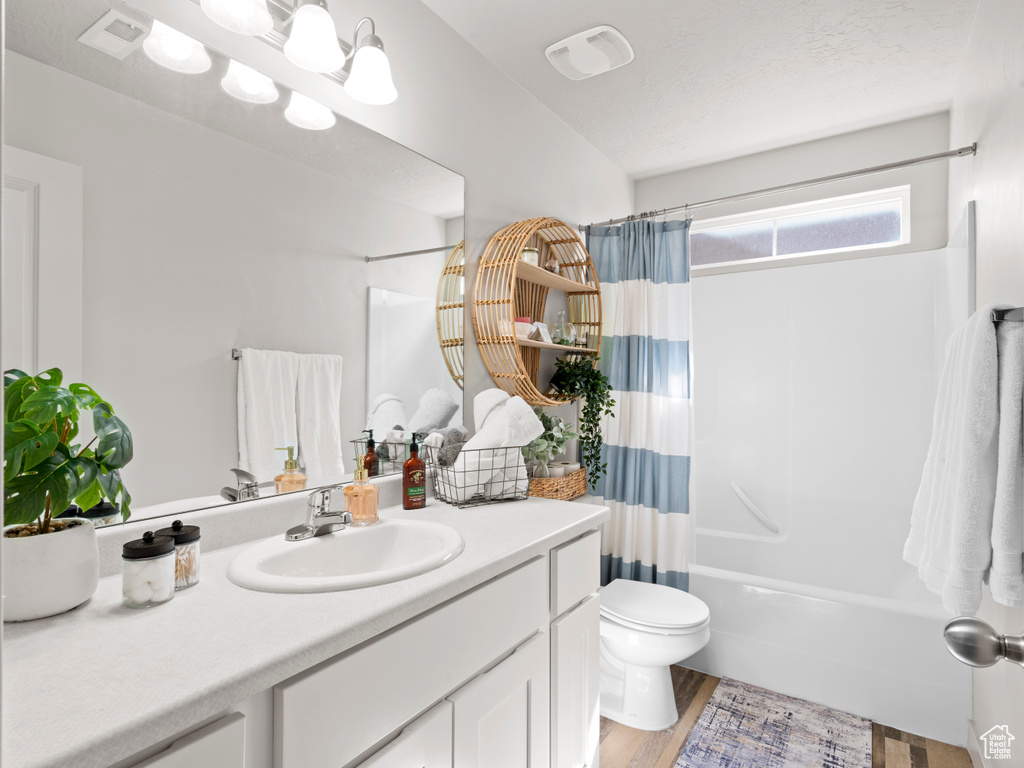 Bathroom featuring vanity, shower / tub combo with curtain, and wood finished floors