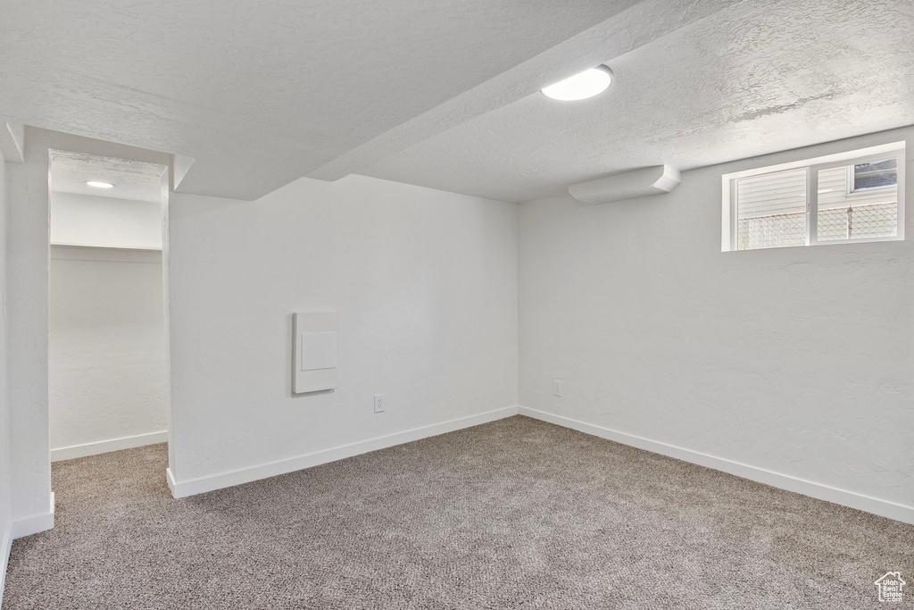Below grade area with carpet and a textured ceiling