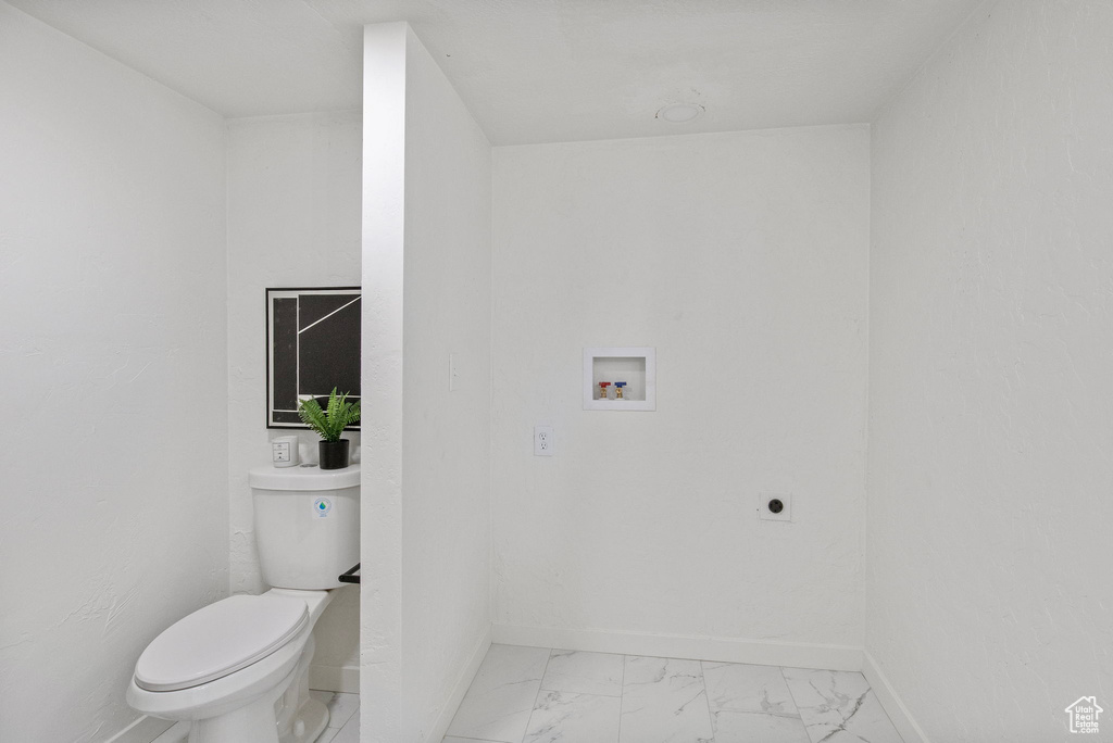 Bathroom featuring marble look tile flooring and toilet