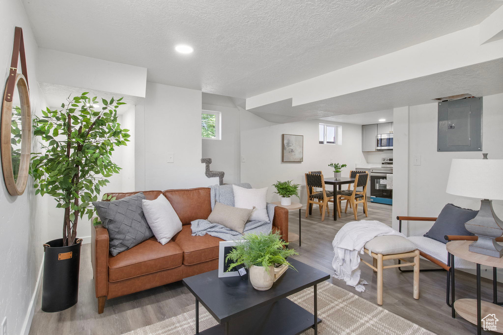 Living area with electric panel, stairway, light wood-style floors, a textured ceiling, and recessed lighting