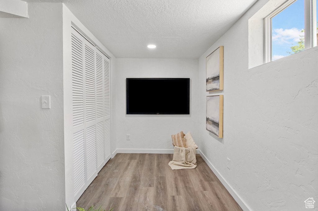 Hall featuring light wood-type flooring, a textured ceiling, and recessed lighting