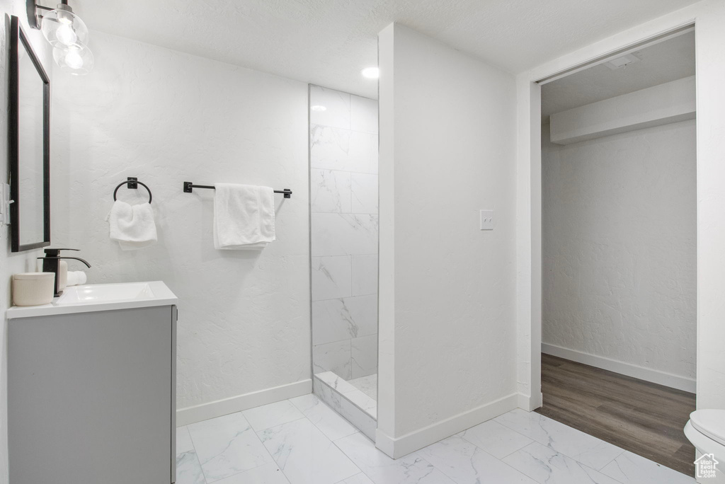 Full bath featuring marble look tile flooring, vanity, and walk in shower