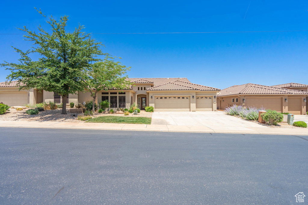 Mediterranean / spanish-style house with an attached garage, concrete driveway, stucco siding, and a tile roof