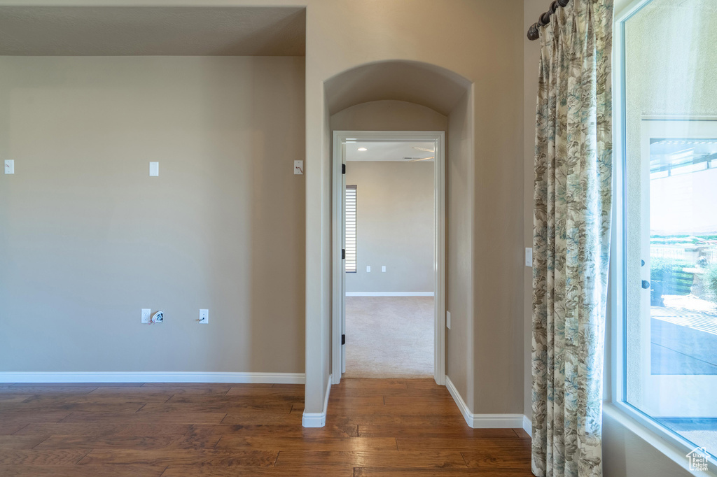 Hall featuring dark wood-style flooring, healthy amount of natural light, and arched walkways
