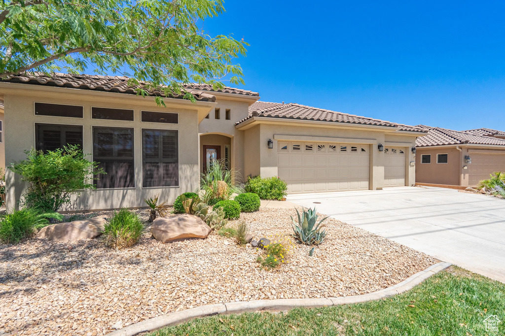Mediterranean / spanish house featuring a garage, concrete driveway, a tile roof, and stucco siding