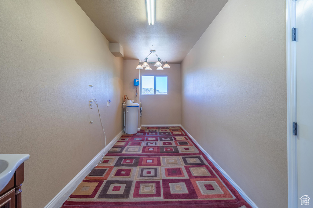 Hallway featuring a chandelier and baseboards