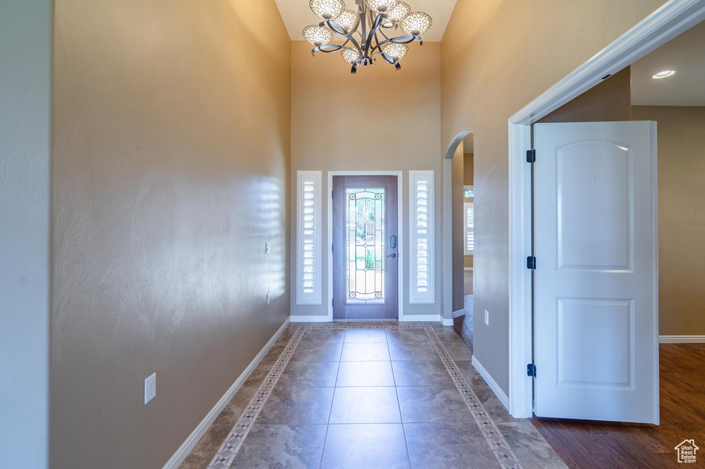 Foyer entrance with arched walkways, a chandelier, a towering ceiling, and tile patterned flooring