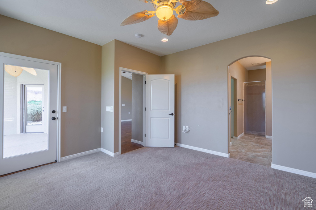 Unfurnished bedroom with arched walkways, carpet floors, a spacious closet, ceiling fan, and recessed lighting