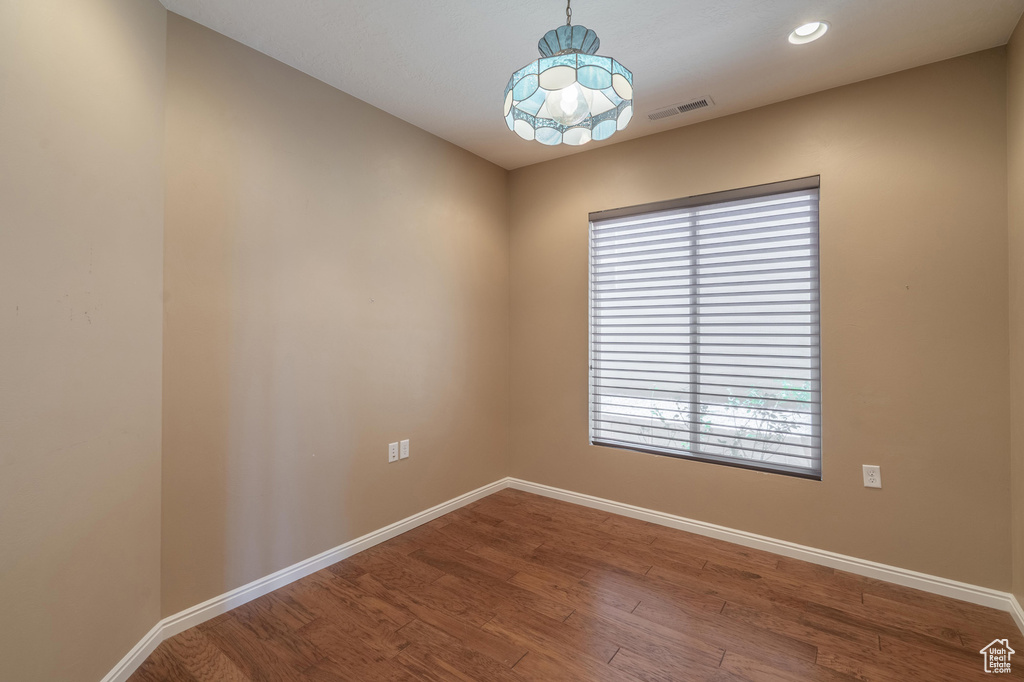 Unfurnished room featuring wood finished floors, recessed lighting, and a chandelier