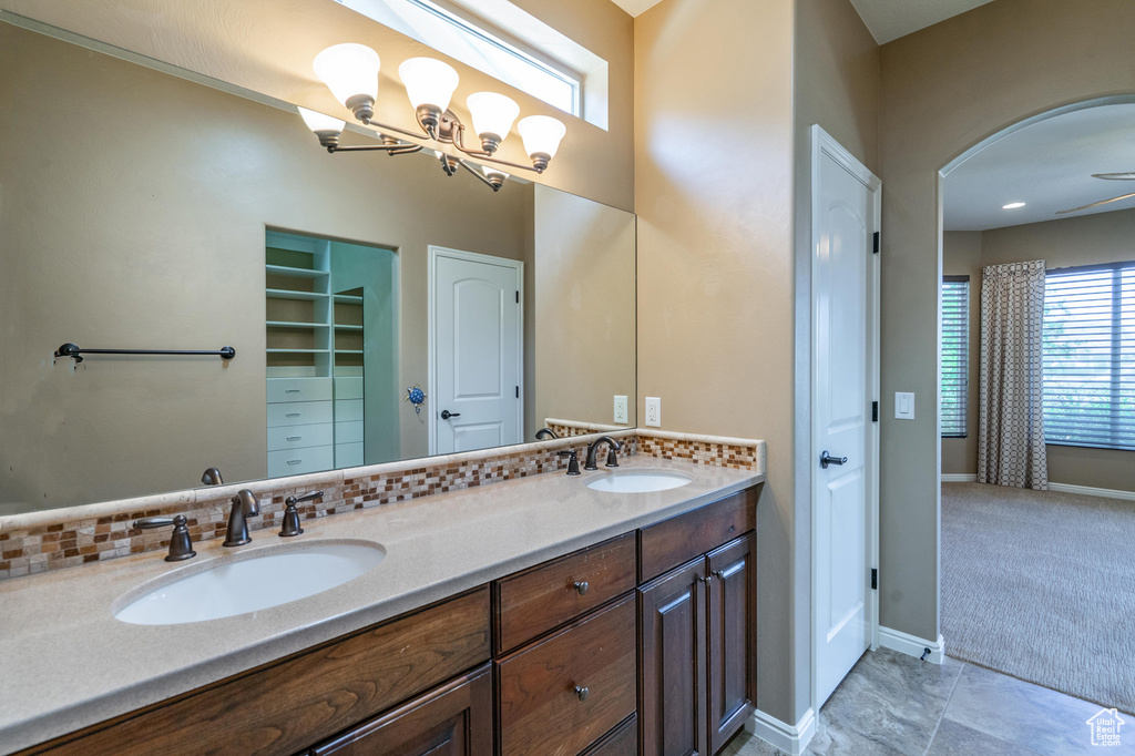 Bathroom with double vanity, a closet, and a chandelier