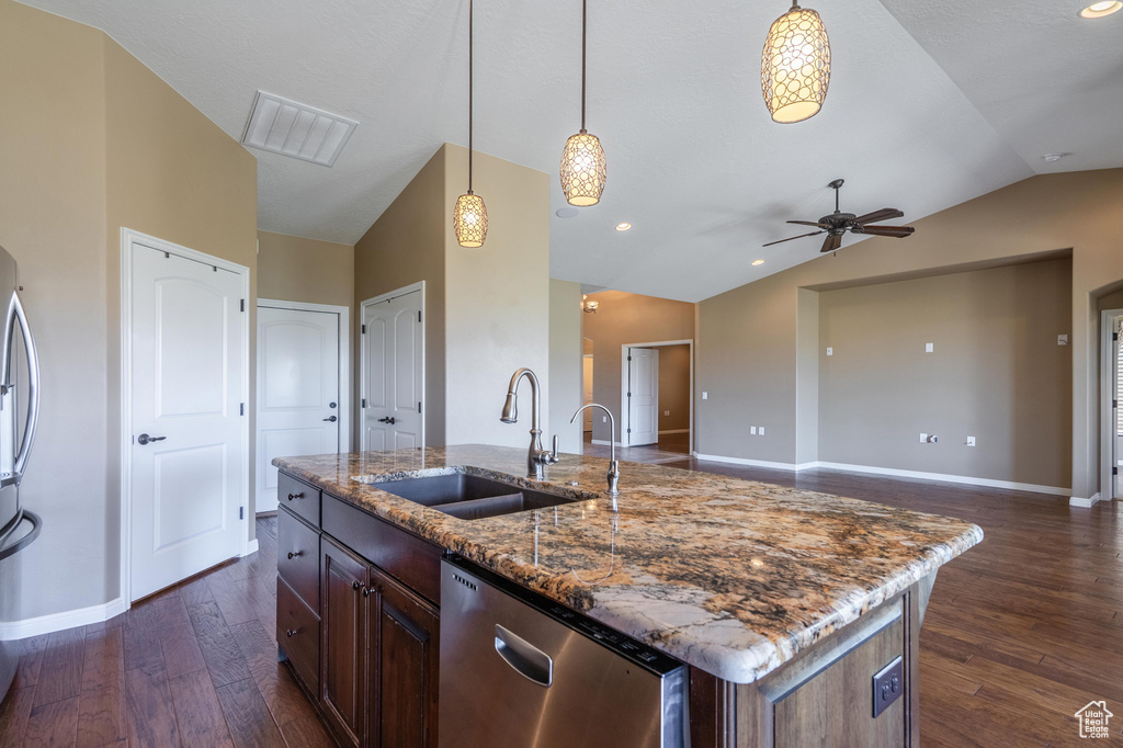Kitchen with appliances with stainless steel finishes, vaulted ceiling, dark wood-style flooring, ceiling fan, and a kitchen island with sink