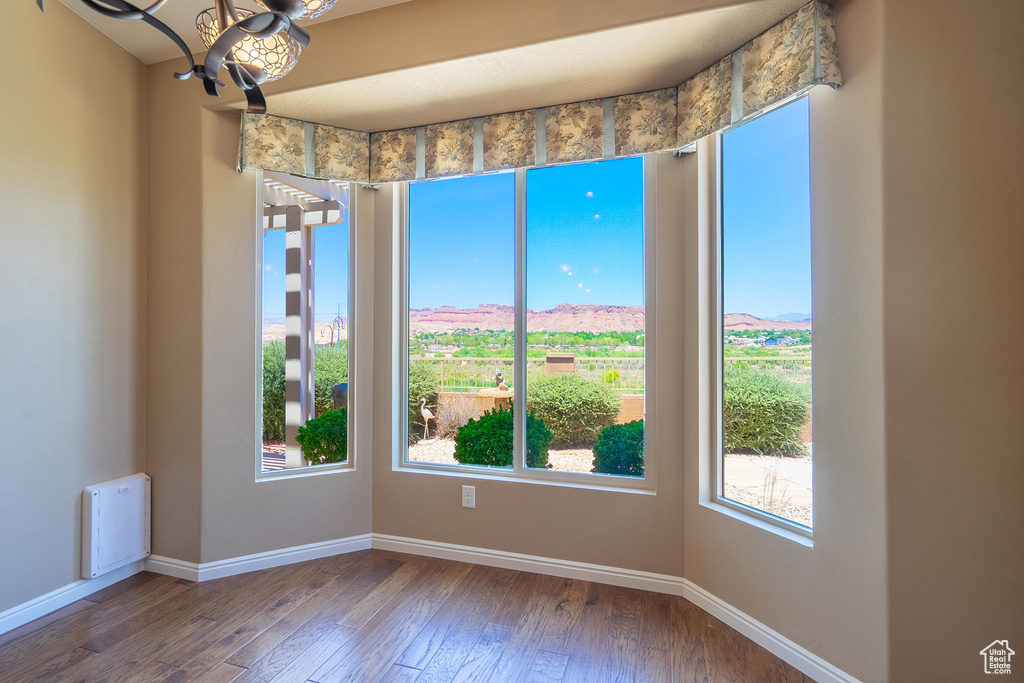 Unfurnished room with plenty of natural light, hardwood / wood-style floors, and a chandelier