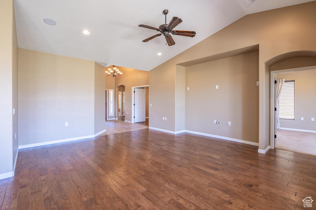 Unfurnished room featuring arched walkways, ceiling fan, lofted ceiling, wood finished floors, and a chandelier
