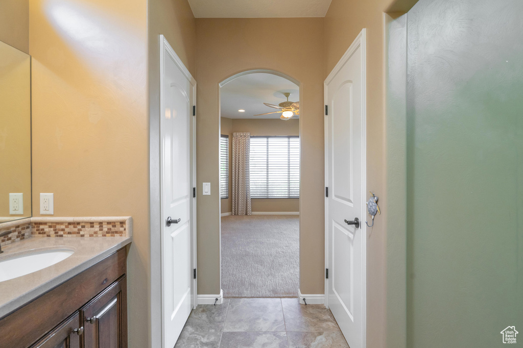 Bathroom featuring a ceiling fan, vanity, and tasteful backsplash