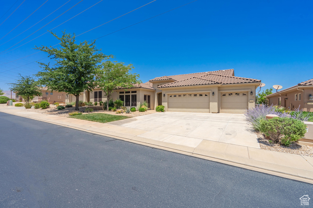 Mediterranean / spanish house with an attached garage, stucco siding, driveway, and a tile roof