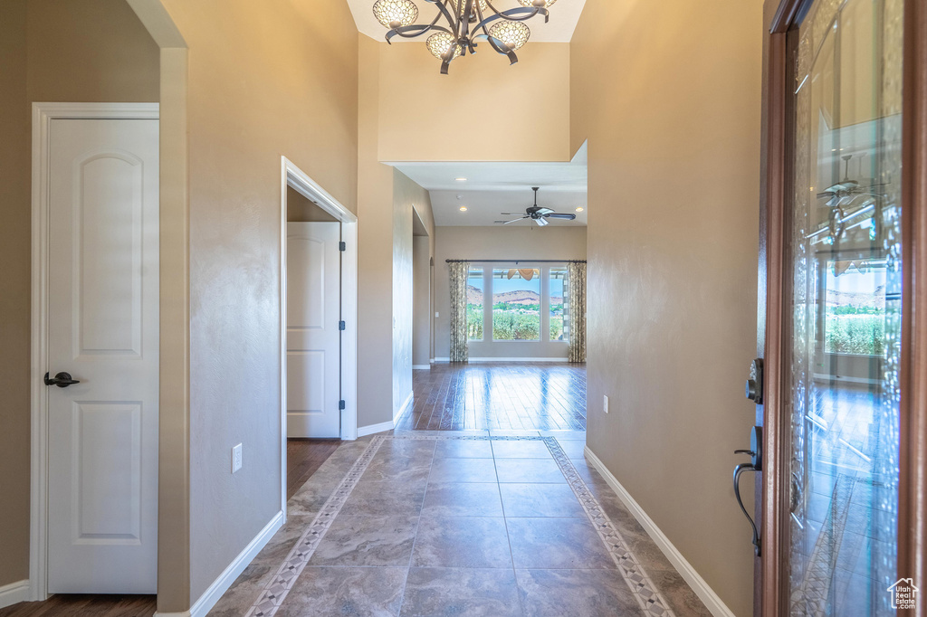 Hall with inlaid floor details, arched walkways, a towering ceiling, and a chandelier
