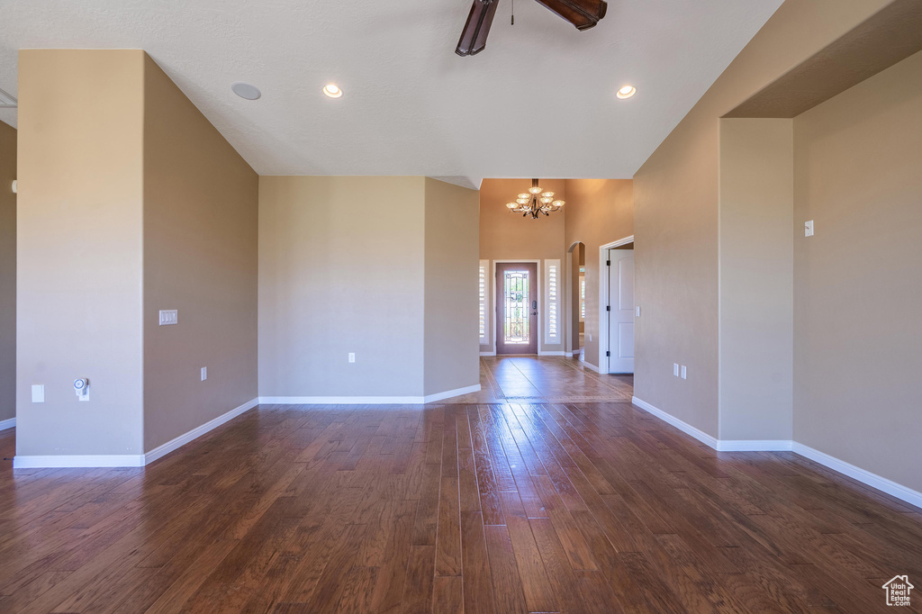 Unfurnished room featuring a chandelier, dark wood-type flooring, ceiling fan, and a high ceiling