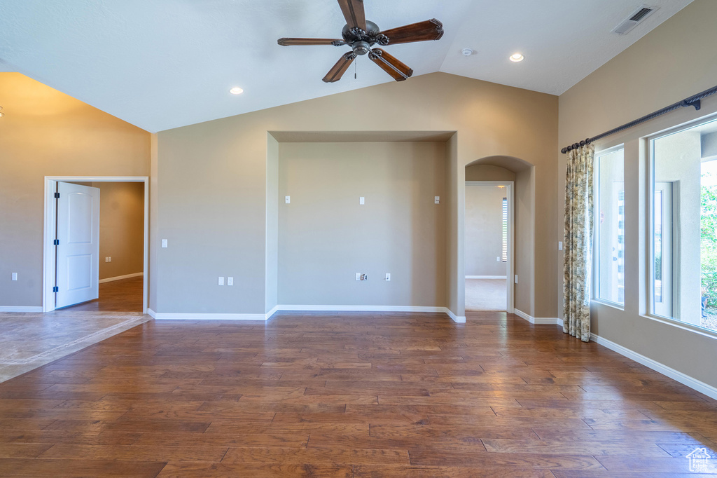 Unfurnished room with arched walkways, lofted ceiling, a ceiling fan, wood finished floors, and recessed lighting
