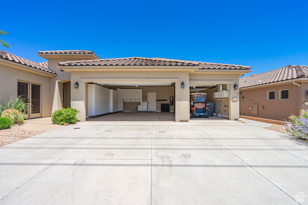 Mediterranean / spanish home featuring driveway, a garage, stucco siding, and a tile roof