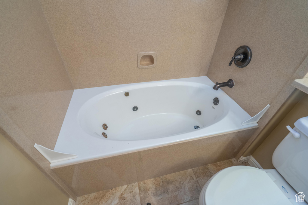 Bathroom featuring a tub with jets and toilet