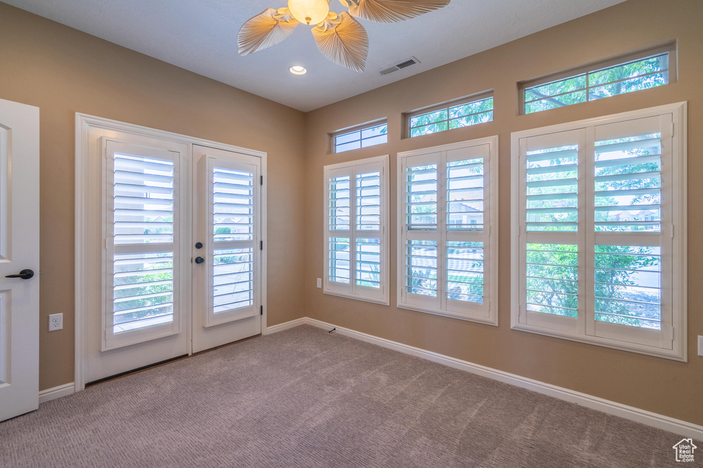 Carpeted spare room featuring plenty of natural light, french doors, and recessed lighting