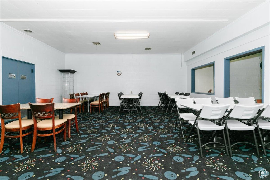 Carpeted dining space featuring ornamental molding