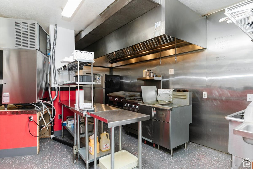 Kitchen with speckle patterned floor, stainless steel countertops, and freestanding refrigerator