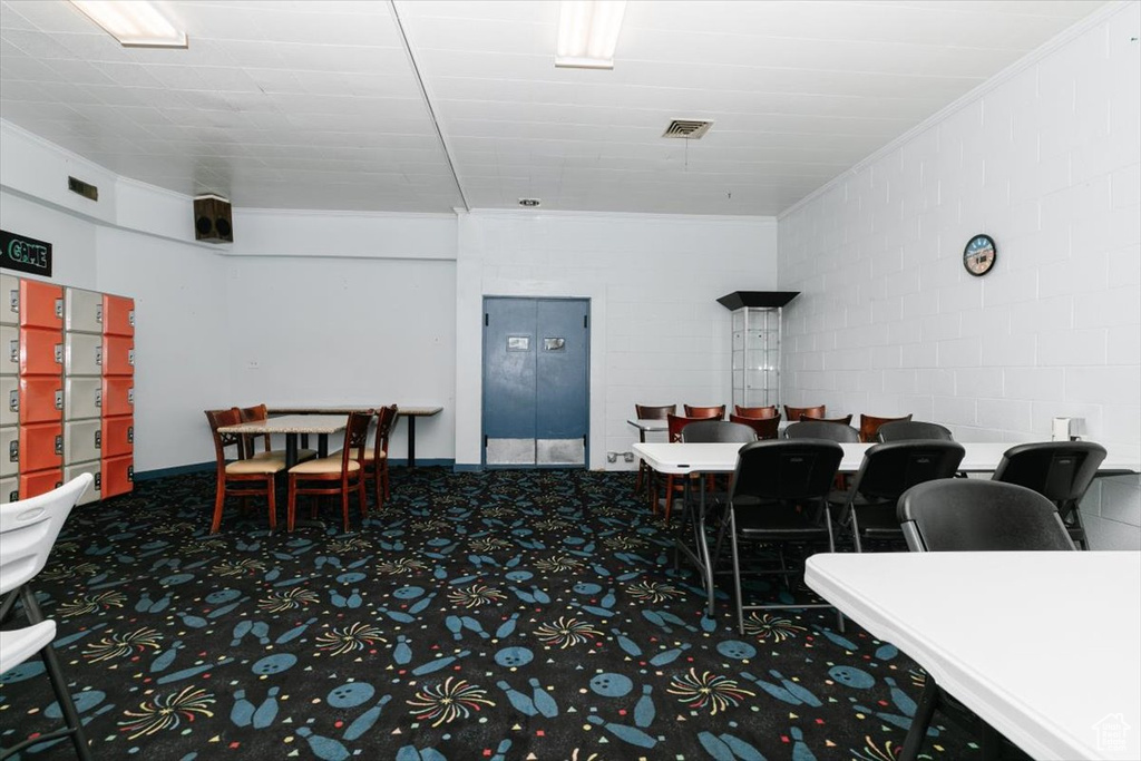 Carpeted dining space featuring concrete block wall and crown molding