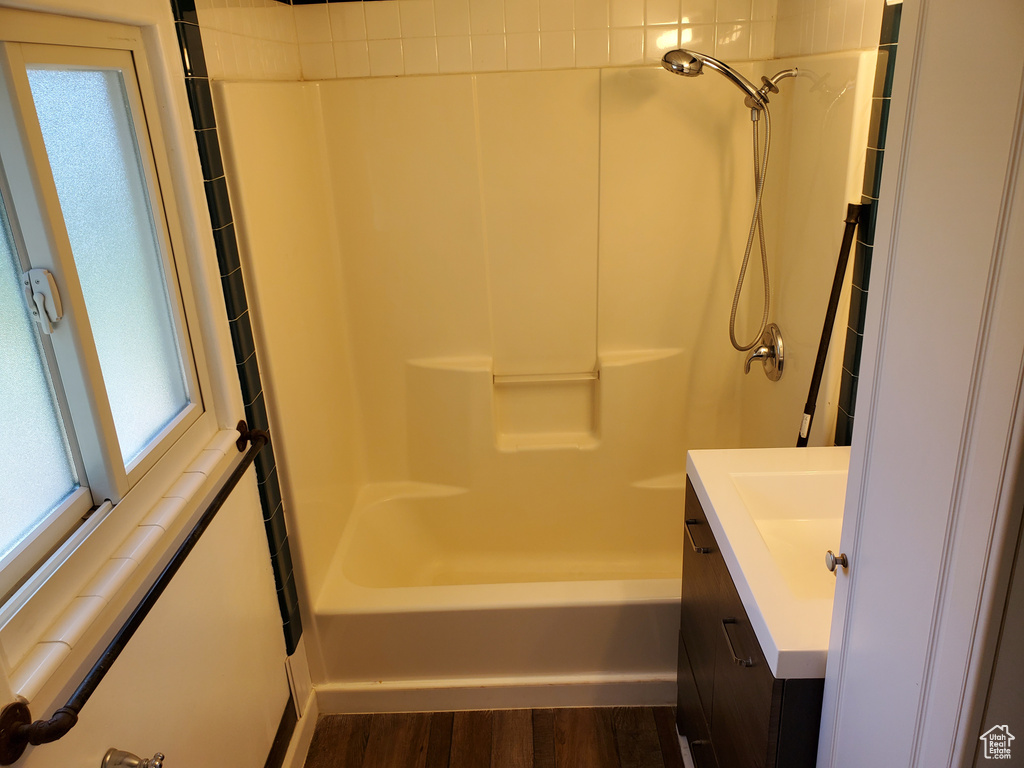 Full bath with healthy amount of natural light, vanity, tub / shower combination, and wood finished floors