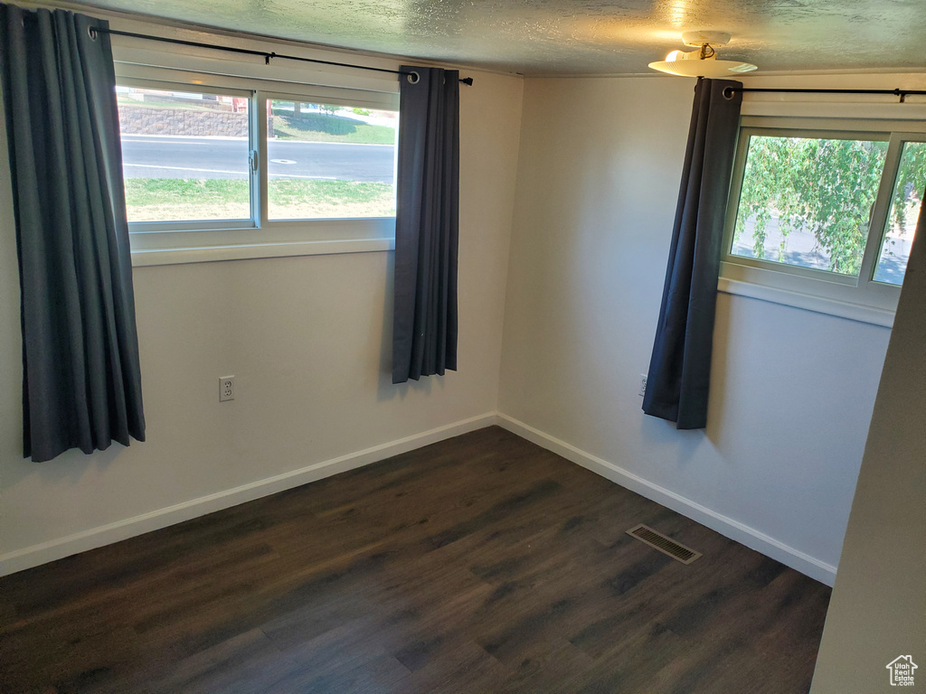 Spare room featuring dark wood-style floors and a textured ceiling