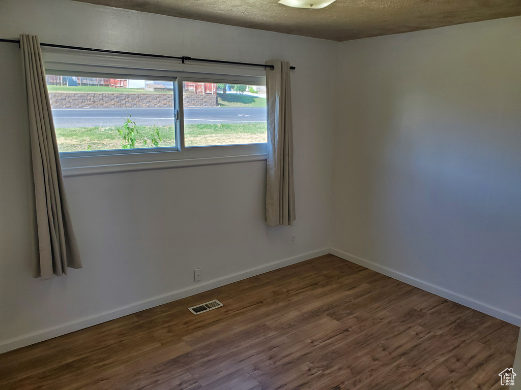 Empty room with wood finished floors and a textured ceiling