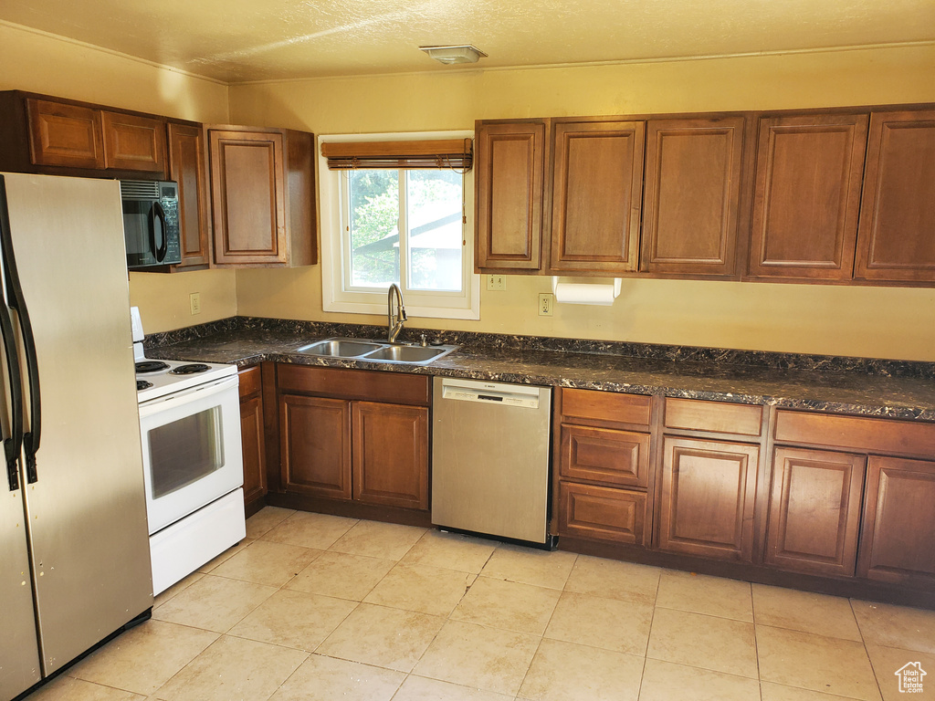 Kitchen with dishwasher, fridge with ice dispenser, white electric range oven, black microwave, and brown cabinetry