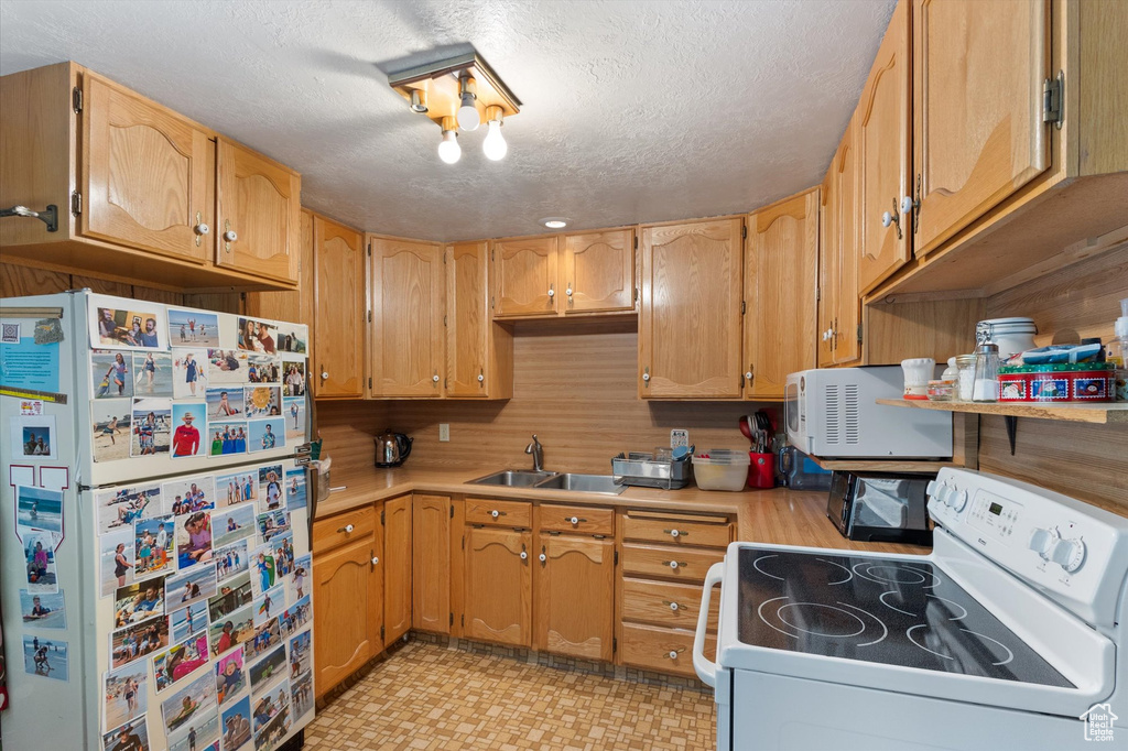 Kitchen with white appliances, light countertops, a textured ceiling, and light flooring