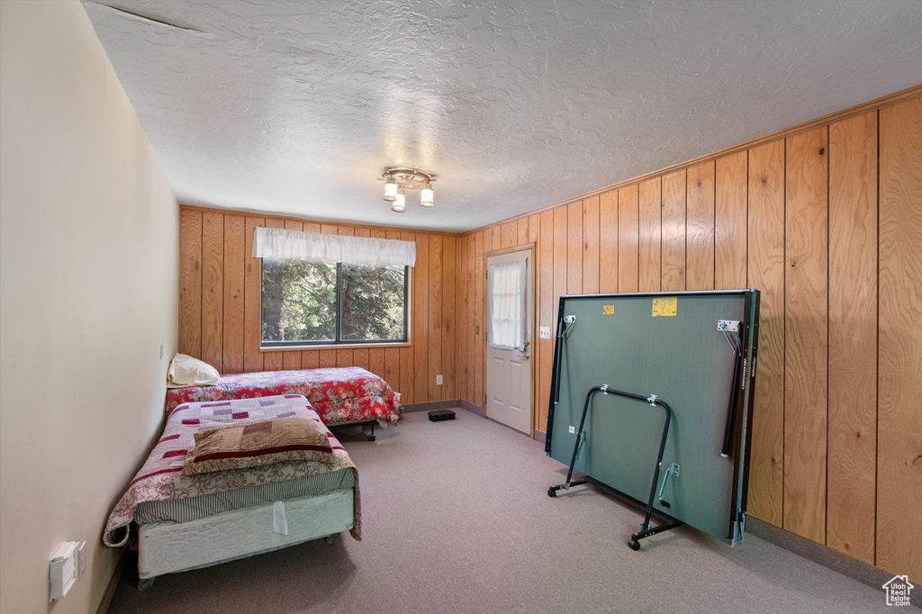 Carpeted bedroom featuring a textured ceiling and wooden walls