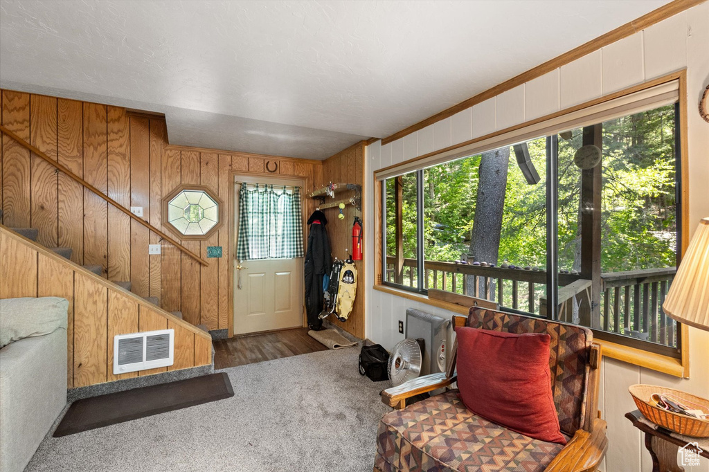 Foyer entrance with carpet, wood walls, and stairs