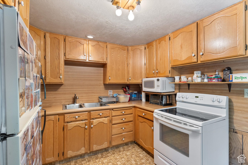 Kitchen with white appliances, light countertops, open shelves, and a textured ceiling