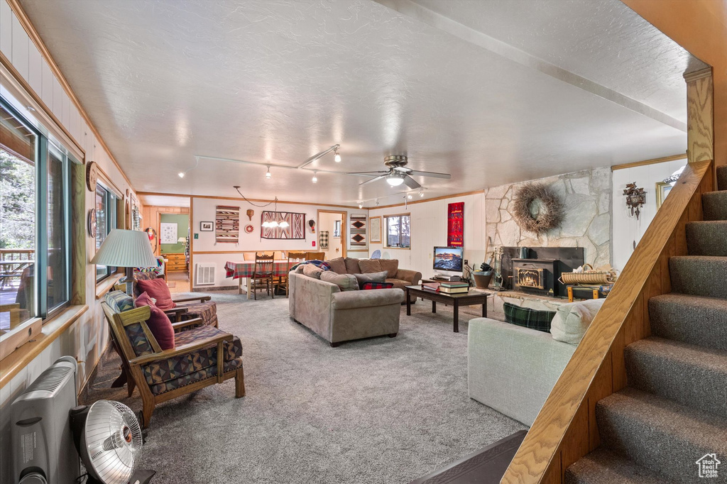 Living room with stairs, carpet flooring, plenty of natural light, and ceiling fan