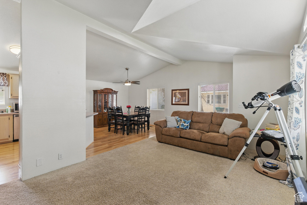 Living area with light wood-type flooring, light colored carpet, and a ceiling fan