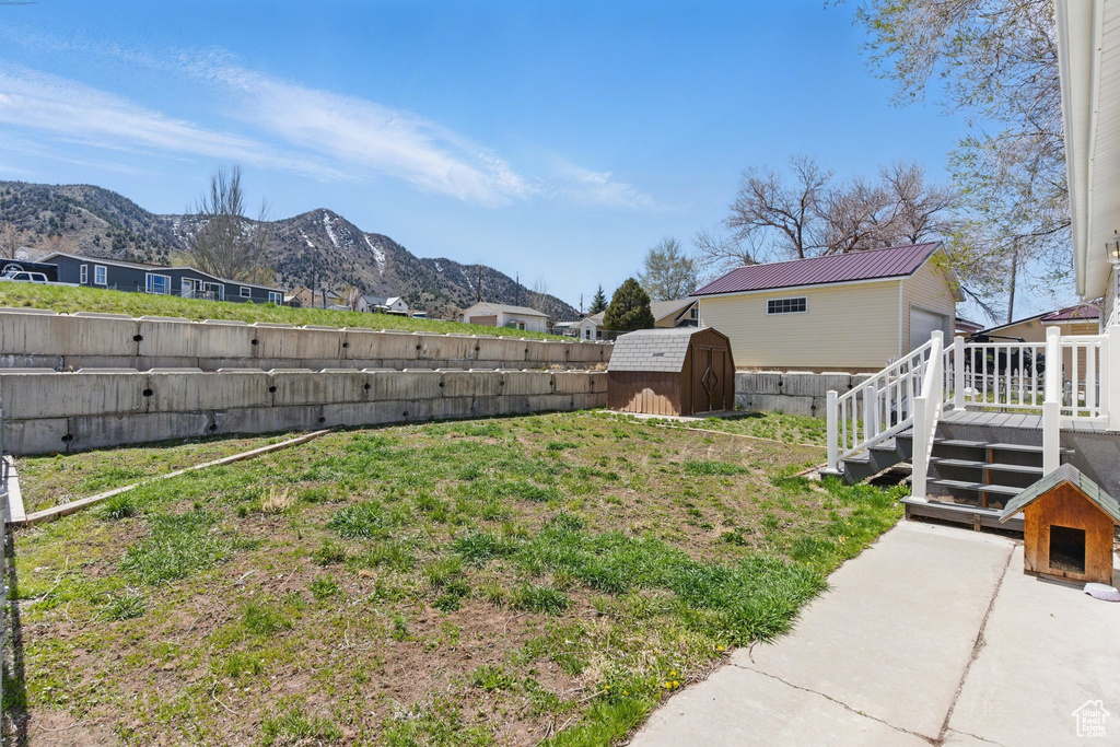 Fenced backyard with a storage unit, a deck with mountain view, and stairway