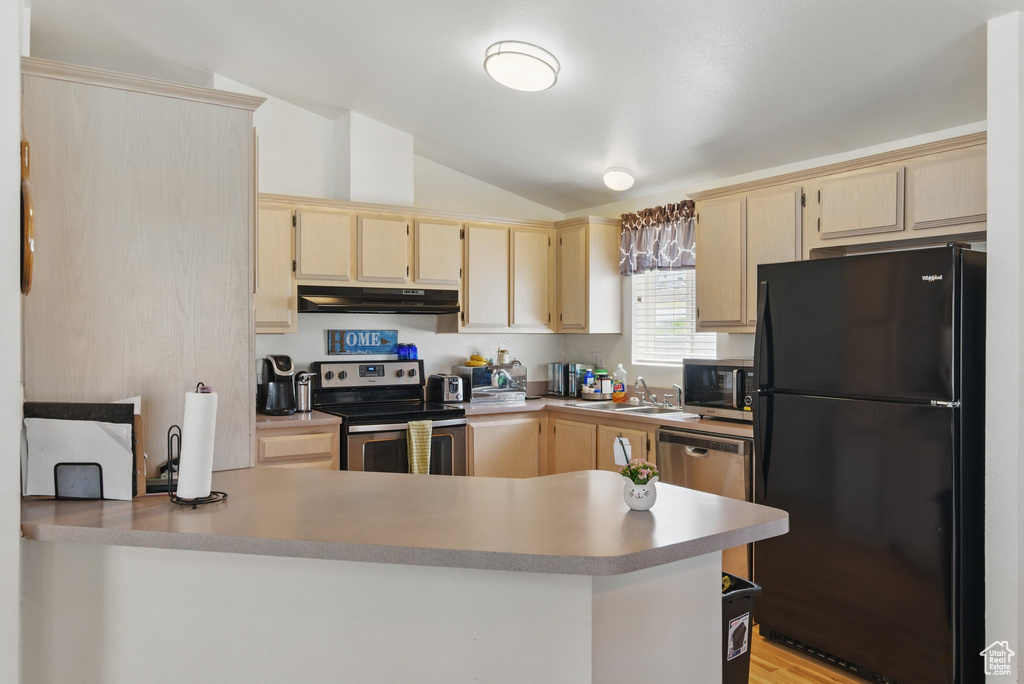 Kitchen with stainless steel appliances, lofted ceiling, light brown cabinetry, a peninsula, and under cabinet range hood