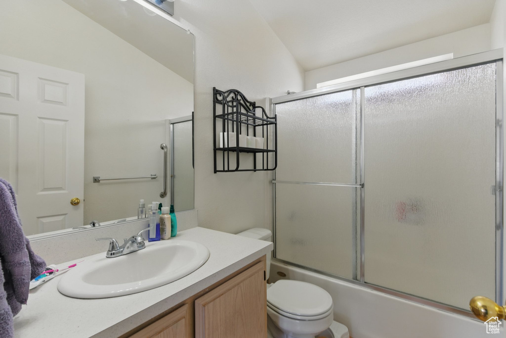Full bathroom with vanity, bath / shower combo with glass door, and lofted ceiling