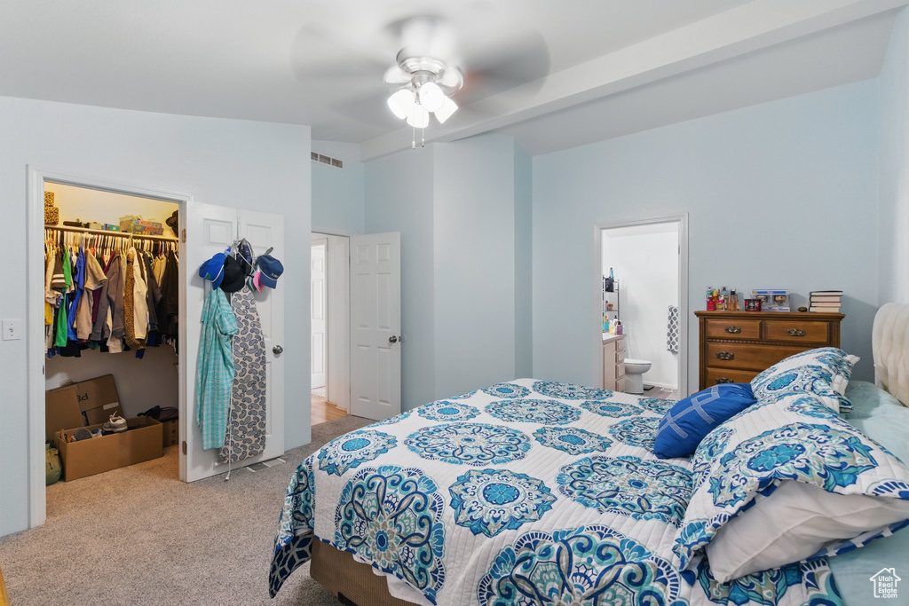 Carpeted bedroom with a walk in closet, a closet, a ceiling fan, ensuite bathroom, and lofted ceiling